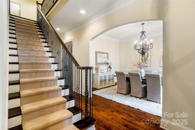 interior space with wood finished floors, recessed lighting, arched walkways, crown molding, and a chandelier