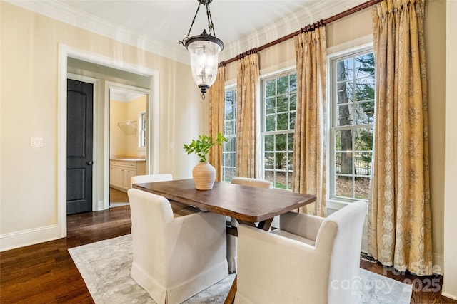 dining space featuring dark wood-style floors, a notable chandelier, crown molding, and baseboards