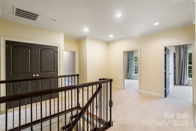 corridor with visible vents, baseboards, light colored carpet, ornamental molding, and an upstairs landing