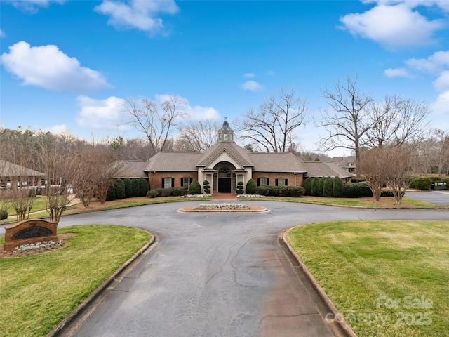 view of front of property with a front lawn, a chimney, and curved driveway