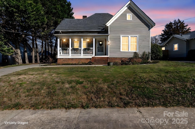 view of front of property featuring a yard, a porch, and a chimney