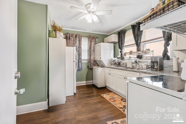 kitchen featuring dark wood-type flooring, white cabinetry, a ceiling fan, stacked washing maching and dryer, and range
