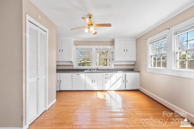 kitchen featuring dark countertops, light wood-type flooring, white cabinets, and a sink