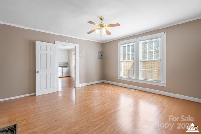 spare room featuring crown molding, light wood finished floors, visible vents, ceiling fan, and baseboards