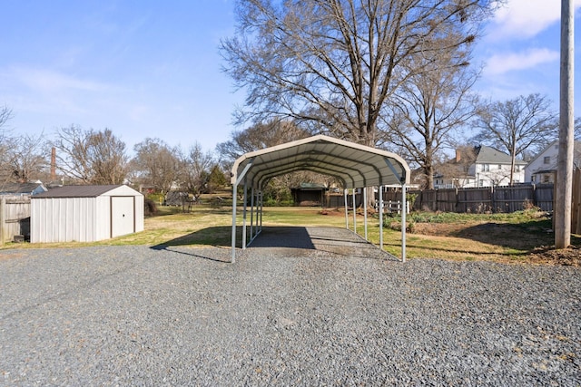 view of parking with a carport, a storage unit, fence, and driveway