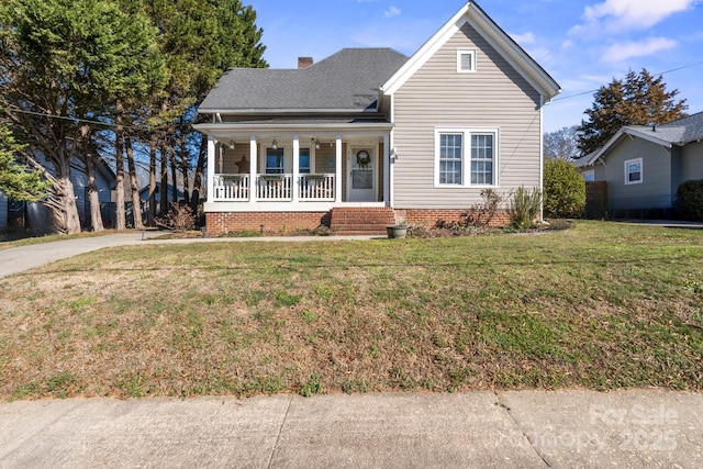 view of front of home with a porch, a front yard, a shingled roof, and a chimney