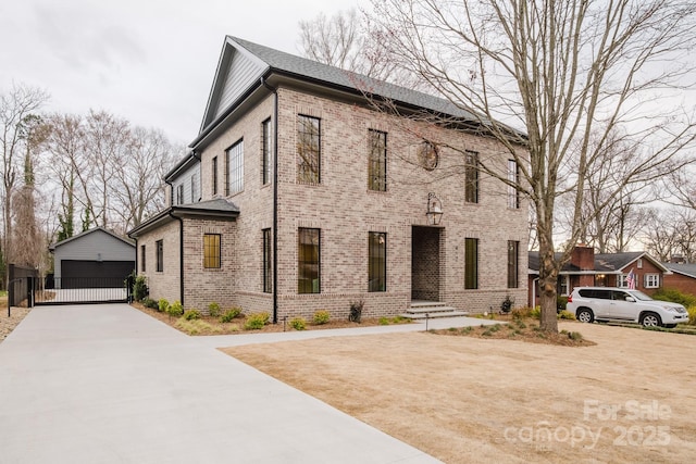 view of front of house featuring a garage, an outbuilding, brick siding, and a gate