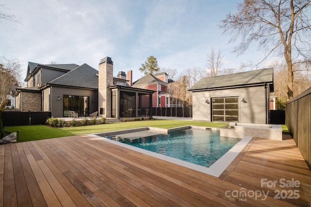 view of swimming pool with an outbuilding, a lawn, a deck, a fenced backyard, and a sunroom