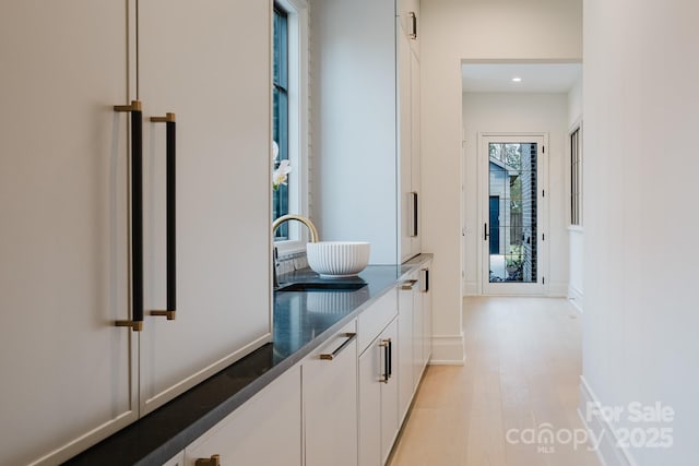 interior space with recessed lighting, light wood-type flooring, baseboards, and a sink