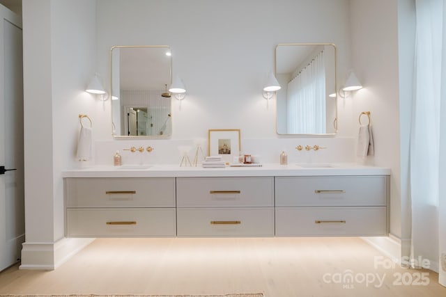 bathroom featuring double vanity, a shower, and a sink