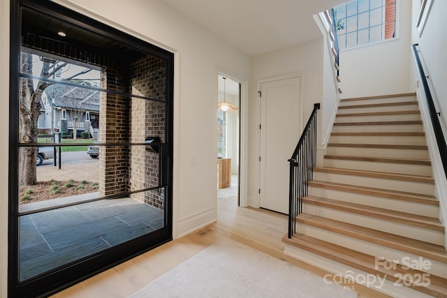 entryway with visible vents, stairs, baseboards, and wood finished floors