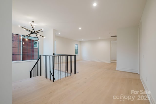 unfurnished room with light wood-type flooring, visible vents, recessed lighting, baseboards, and a chandelier