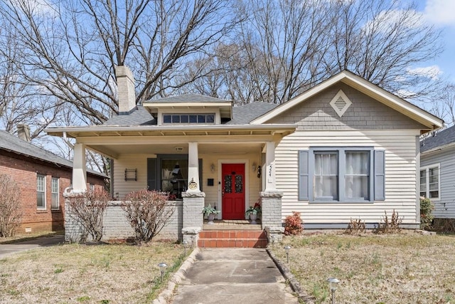 bungalow-style home featuring covered porch and a chimney