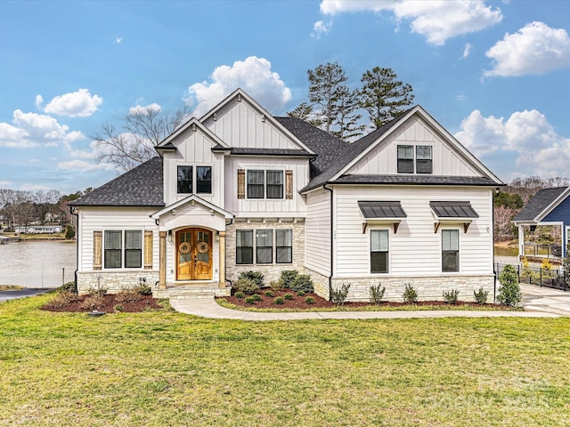 modern farmhouse with board and batten siding, a front lawn, stone siding, and roof with shingles