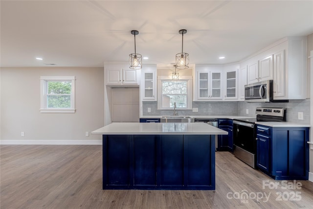 kitchen with light countertops, decorative backsplash, stainless steel appliances, blue cabinets, and a sink