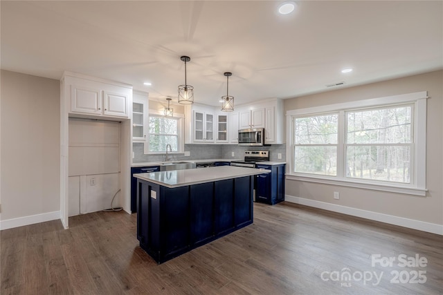 kitchen with dark wood-style floors, white cabinetry, stainless steel appliances, and light countertops