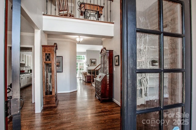 hallway with stairs, dark wood-style floors, baseboards, and a towering ceiling