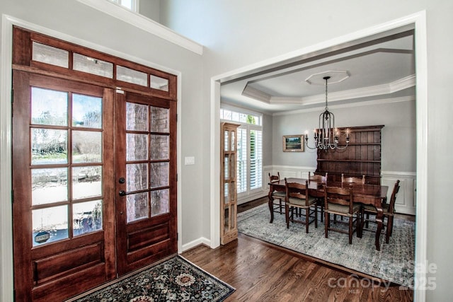 entryway featuring a wainscoted wall, a tray ceiling, dark wood-style flooring, french doors, and a chandelier