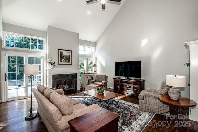 living room with a ceiling fan, high vaulted ceiling, wood finished floors, and a high end fireplace