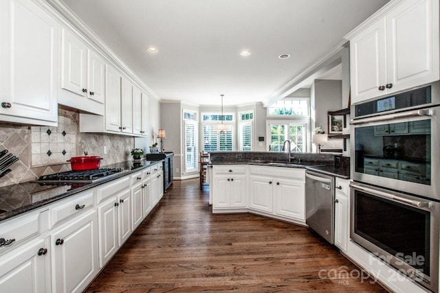 kitchen featuring a sink, backsplash, white cabinetry, stainless steel appliances, and a peninsula