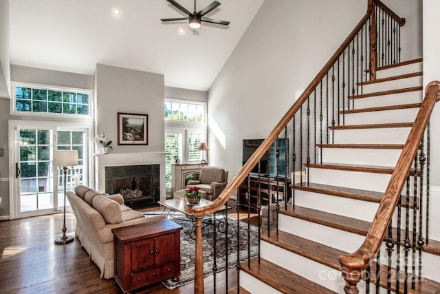 living room with a fireplace, high vaulted ceiling, stairs, and wood finished floors