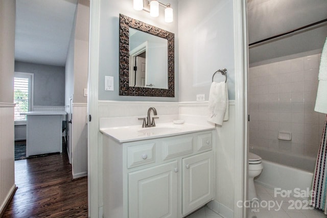 bathroom with vanity, wood finished floors, tub / shower combination, wainscoting, and toilet