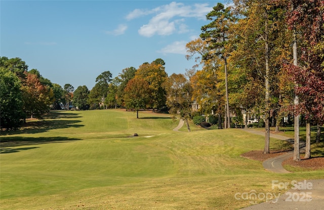 view of property's community with view of golf course and a lawn