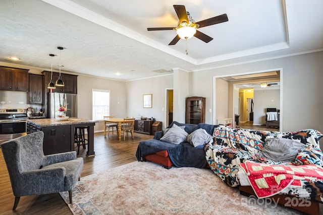 living room with dark wood-style floors, ceiling fan, a raised ceiling, and crown molding