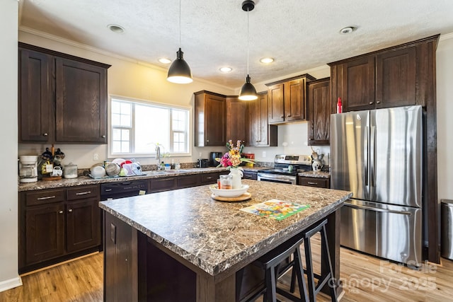 kitchen with light wood-style flooring, appliances with stainless steel finishes, hanging light fixtures, a textured ceiling, and dark brown cabinets