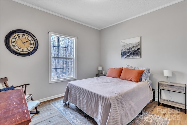 bedroom featuring ornamental molding, baseboards, and wood finished floors