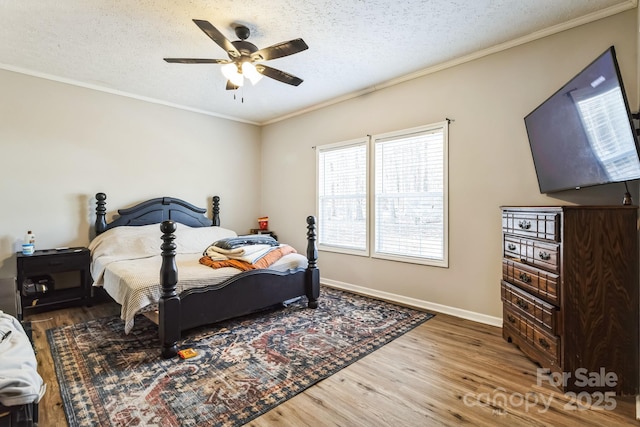 bedroom featuring a textured ceiling, ceiling fan, wood finished floors, baseboards, and crown molding