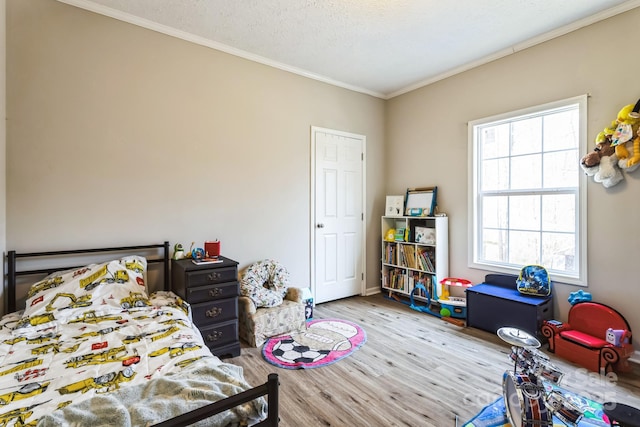 bedroom featuring ornamental molding, a textured ceiling, and wood finished floors