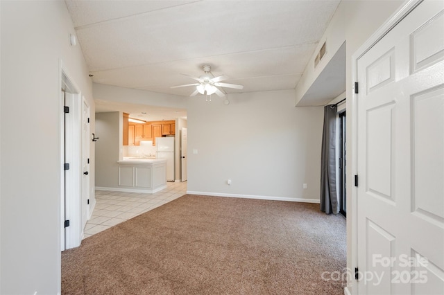 unfurnished bedroom with visible vents, baseboards, ensuite bath, freestanding refrigerator, and light colored carpet