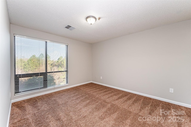 spare room featuring baseboards, visible vents, carpet floors, and a textured ceiling