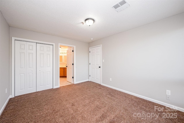 unfurnished bedroom featuring visible vents, baseboards, light colored carpet, a closet, and a textured ceiling