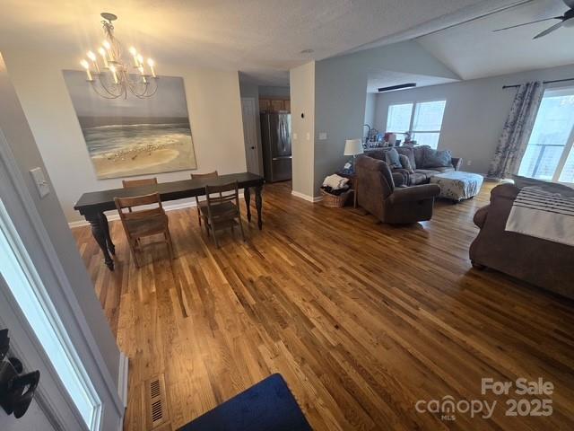 living room with ceiling fan with notable chandelier, baseboards, and wood finished floors