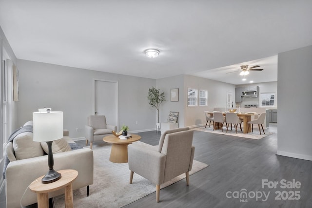 living room featuring dark wood-style floors, a ceiling fan, and baseboards