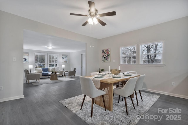 dining space with a ceiling fan, baseboards, and dark wood-type flooring