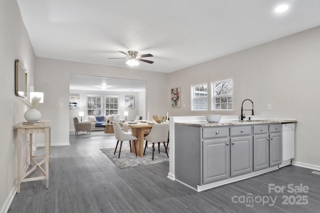 kitchen with dark wood finished floors, gray cabinets, light countertops, a sink, and baseboards