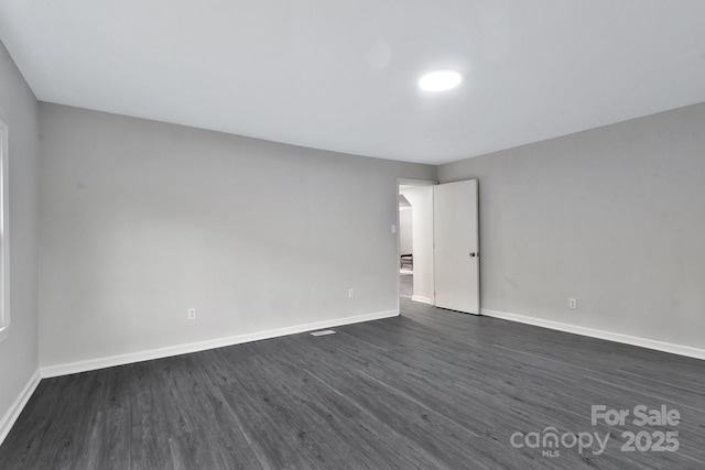 spare room with dark wood-type flooring and baseboards