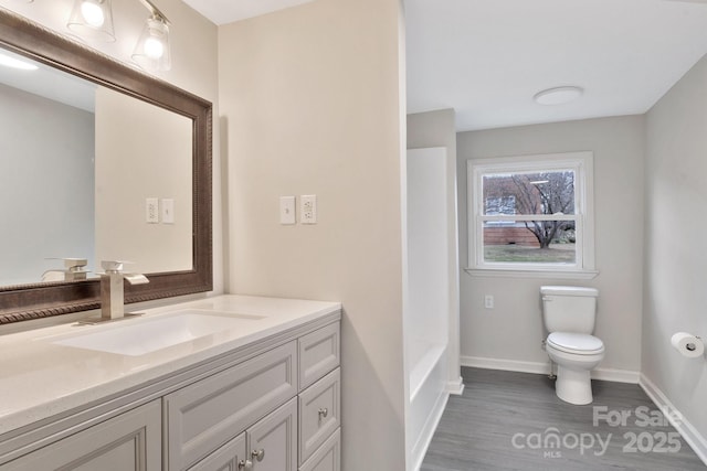 bathroom with baseboards, a shower, toilet, wood finished floors, and vanity