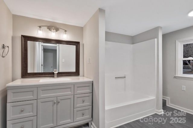 bathroom featuring shower / bath combination, wood finished floors, vanity, and baseboards