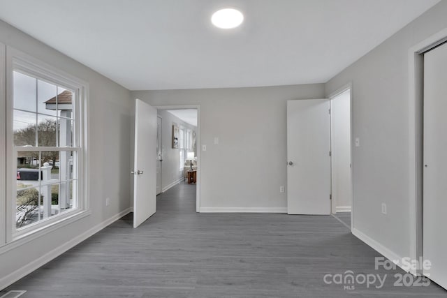 spare room with baseboards, a wealth of natural light, and wood finished floors