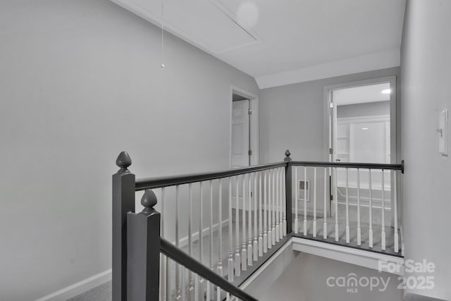 corridor with attic access, baseboards, and an upstairs landing