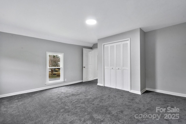 unfurnished bedroom featuring dark colored carpet, a closet, and baseboards