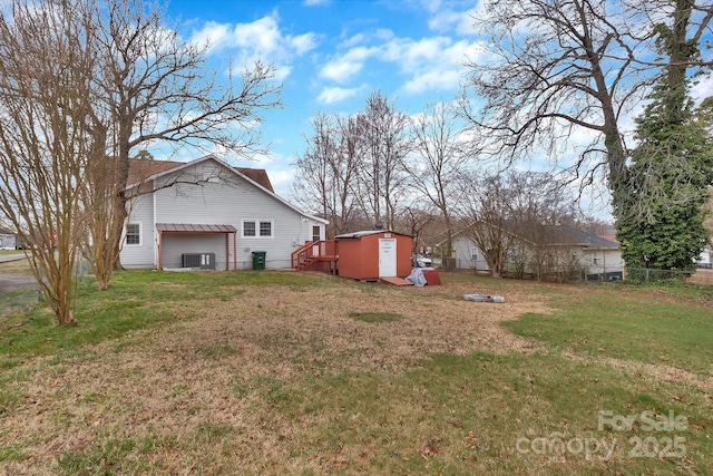 view of yard with fence, a storage unit, central AC, and an outdoor structure