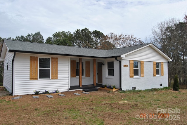 single story home with brick siding, a porch, a front yard, roof with shingles, and crawl space