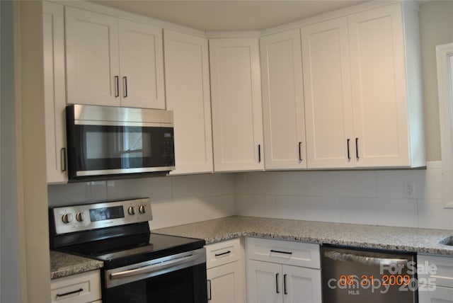 kitchen featuring white cabinetry, light stone countertops, backsplash, and stainless steel appliances