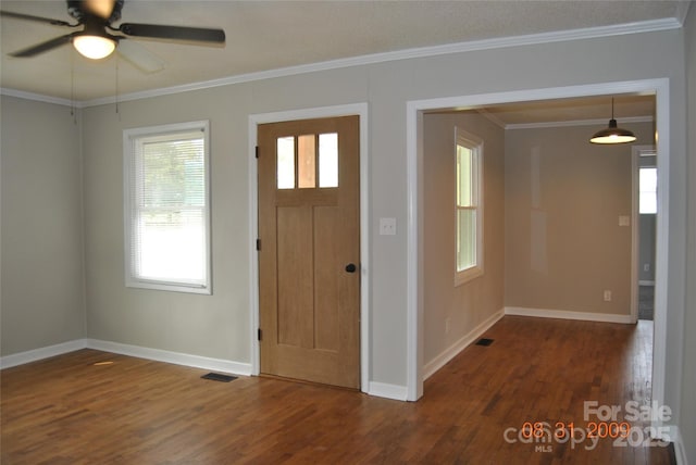 foyer entrance with visible vents, crown molding, baseboards, and wood finished floors