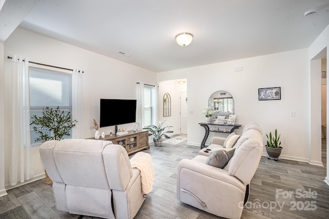 living area with visible vents, baseboards, and wood finished floors